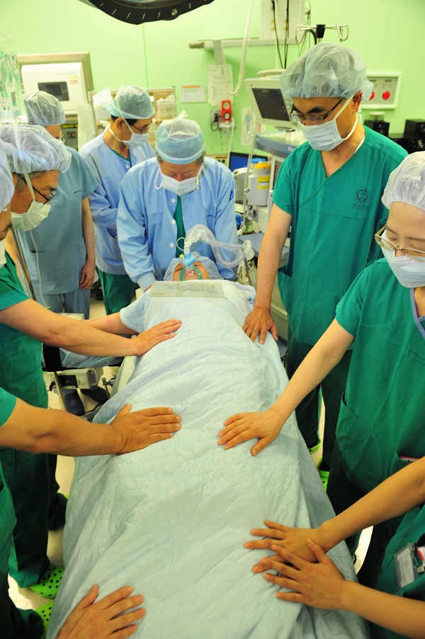 이철 장로가 수술 전 환자를 위해 의료진들과 함께 손을 얹고 기도하고 있다.